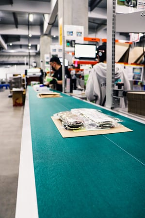 緑ベルトコンベア上の梱包品（アパレル袋）クローズアップ