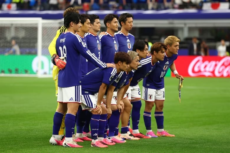 W杯2026 日本代表の集合写真。青のユニフォームの足元にピンクのスパイクが並ぶ