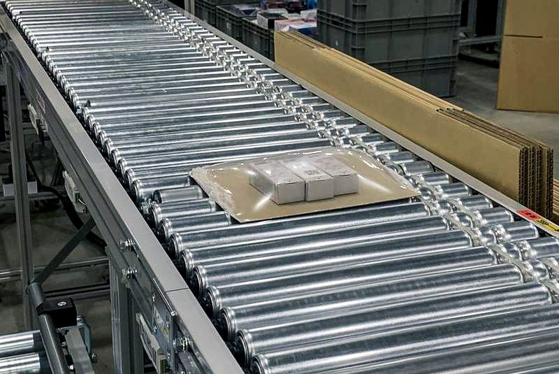 出荷コンベア上を流れるフラットベルトと梱包済み商品