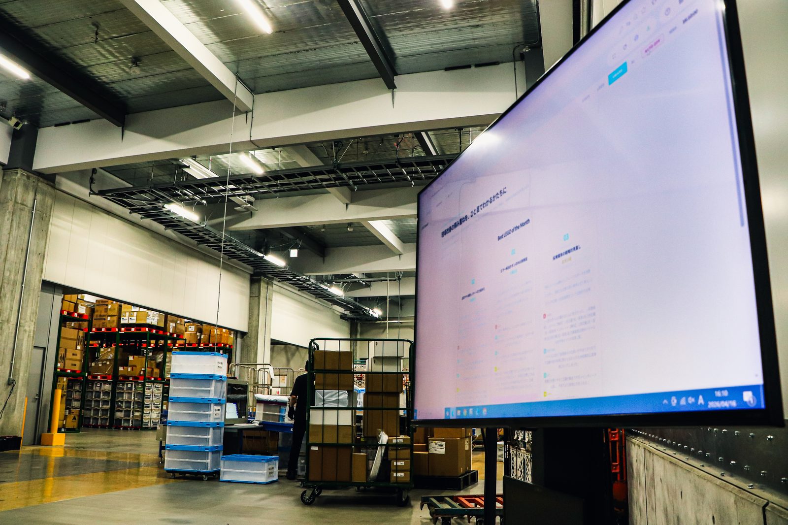 倉庫内の大型WMS管理モニター（倉庫全景と共に）